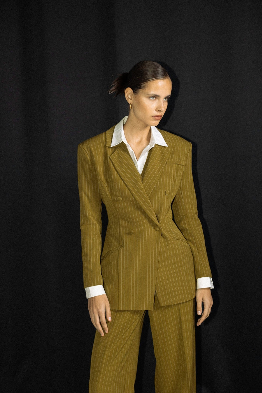 Woman wearing moss green sculpted ALALYA blazer in gallery setting – Dubai luxury fashion